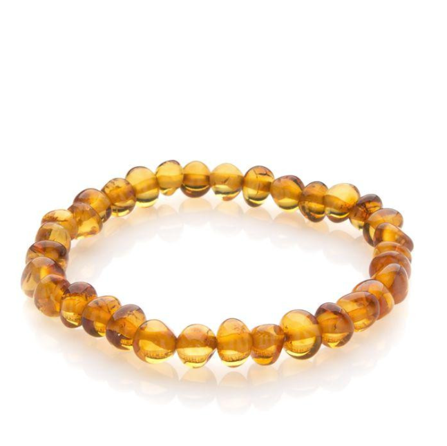 Een kralenarmband gemaakt van gepolijste, doorschijnende honingkleurige amberkleurige kralen die in een cirkel op een witte achtergrond zijn gerangschikt.