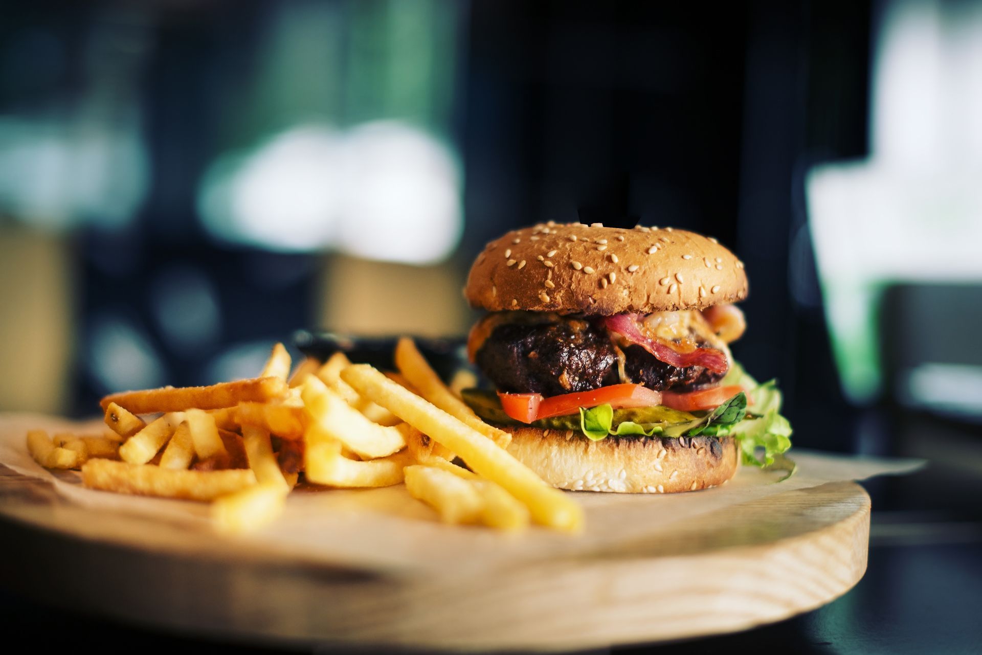 A hamburger and french fries are on a wooden cutting board.