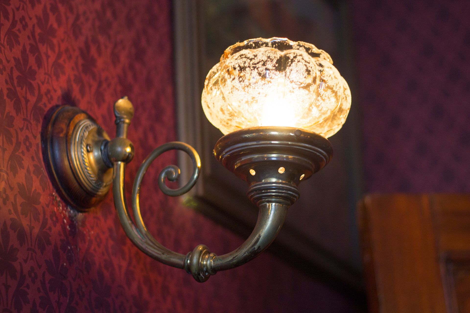 A brass wall light with a clear glass shade