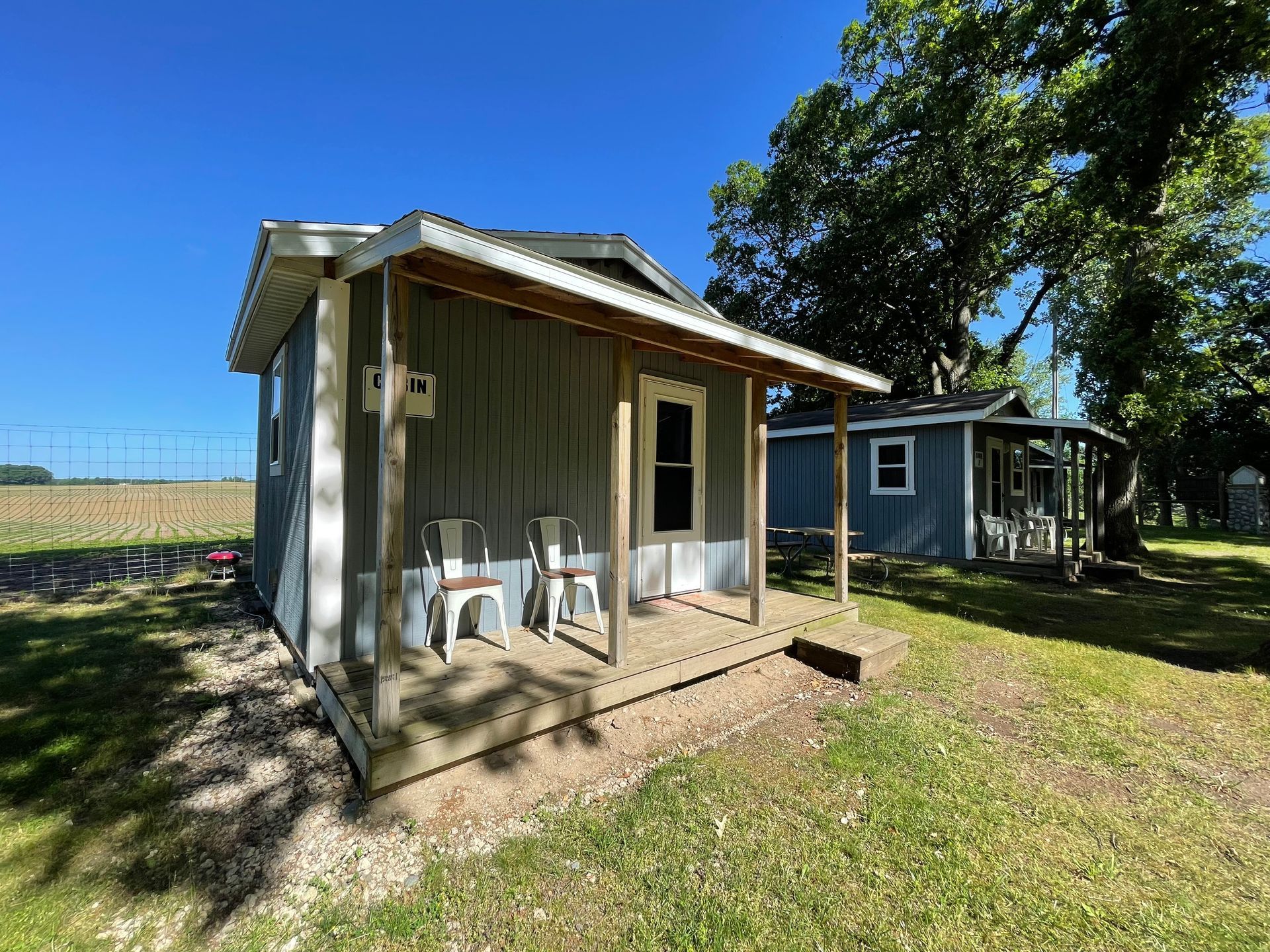 A small house with a porch and chairs in a field.