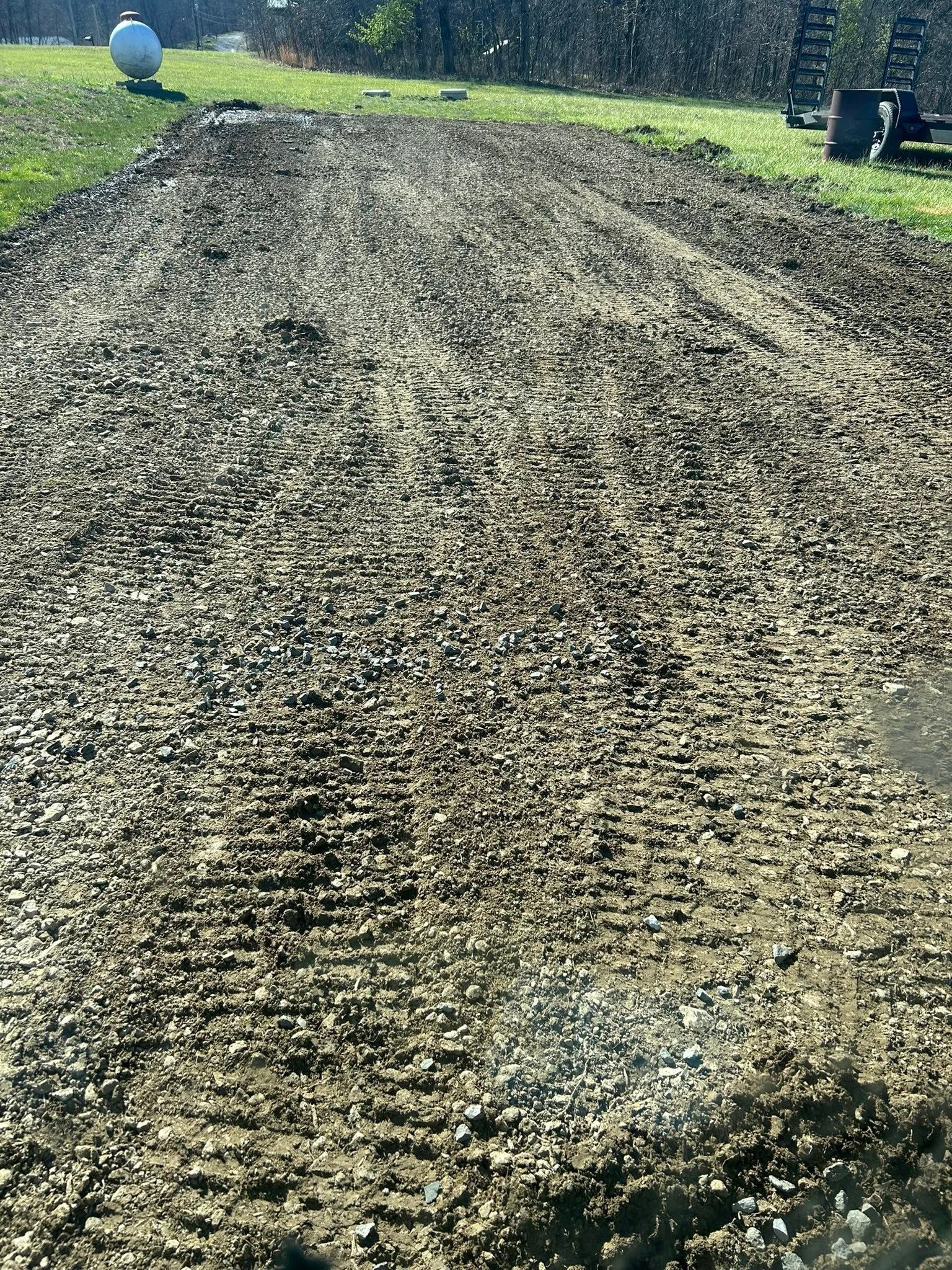 Freshly tilled gravel or dirt field with a rough textured surface under daylight