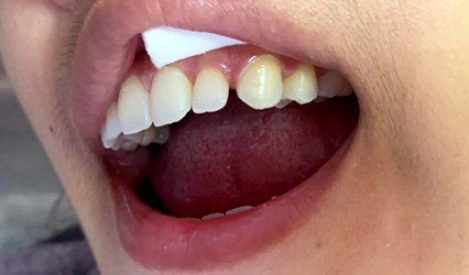 A close up of a person 's mouth with a piece of paper in it.