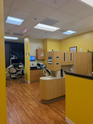 Hospital reception area with wood flooring, beige counters, computers, and overhead fluorescent lights