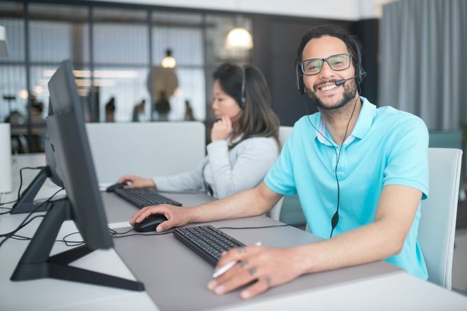 A man wearing a headset is sitting at a desk in front of a computer.