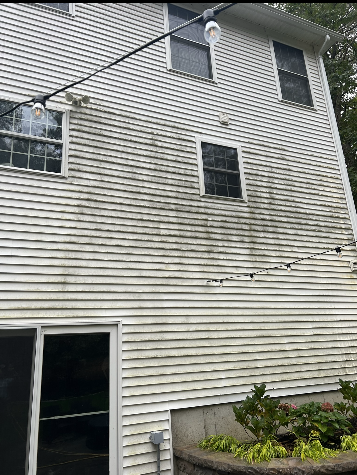 The back of a white house with a lot of stains on it.