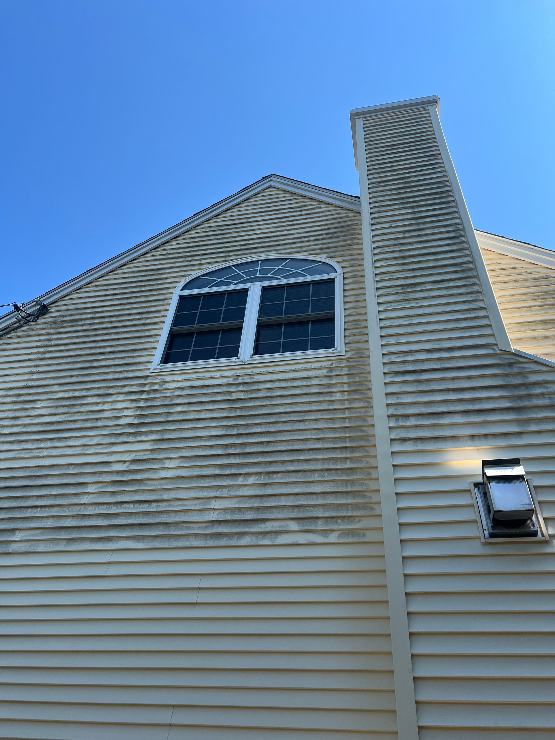 The side of a house with a chimney and a window.