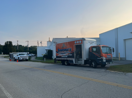 A moving truck is parked on the side of the road in front of a building.