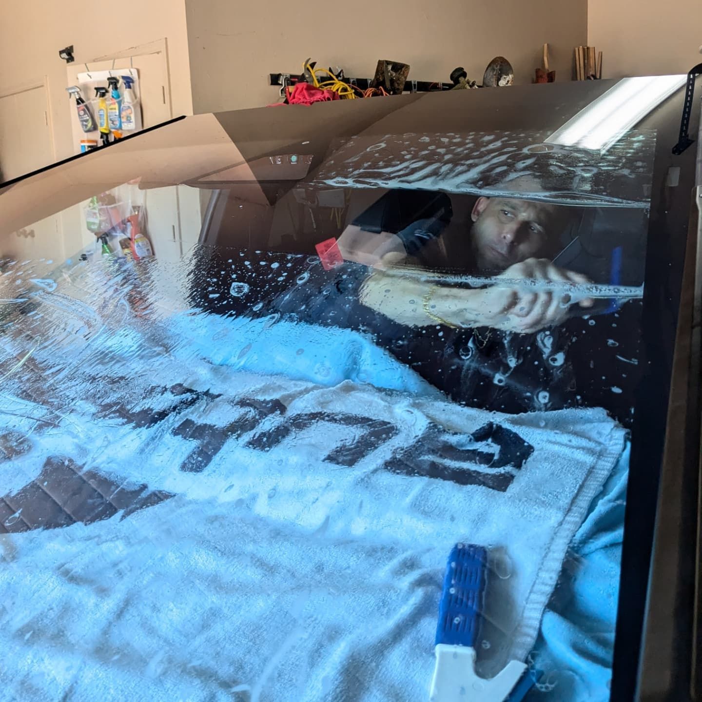 A man is cleaning the windshield of a car with a towel