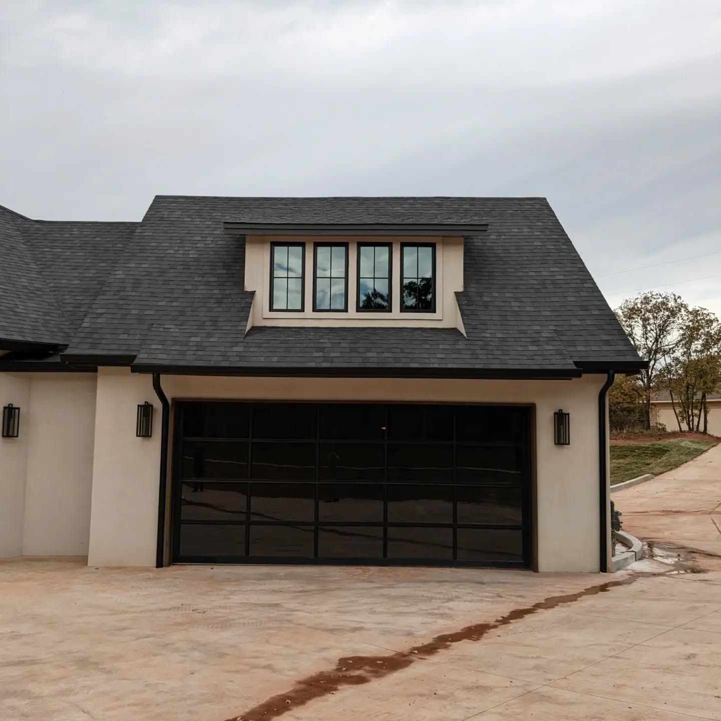 A white house with a black garage door and a black roof