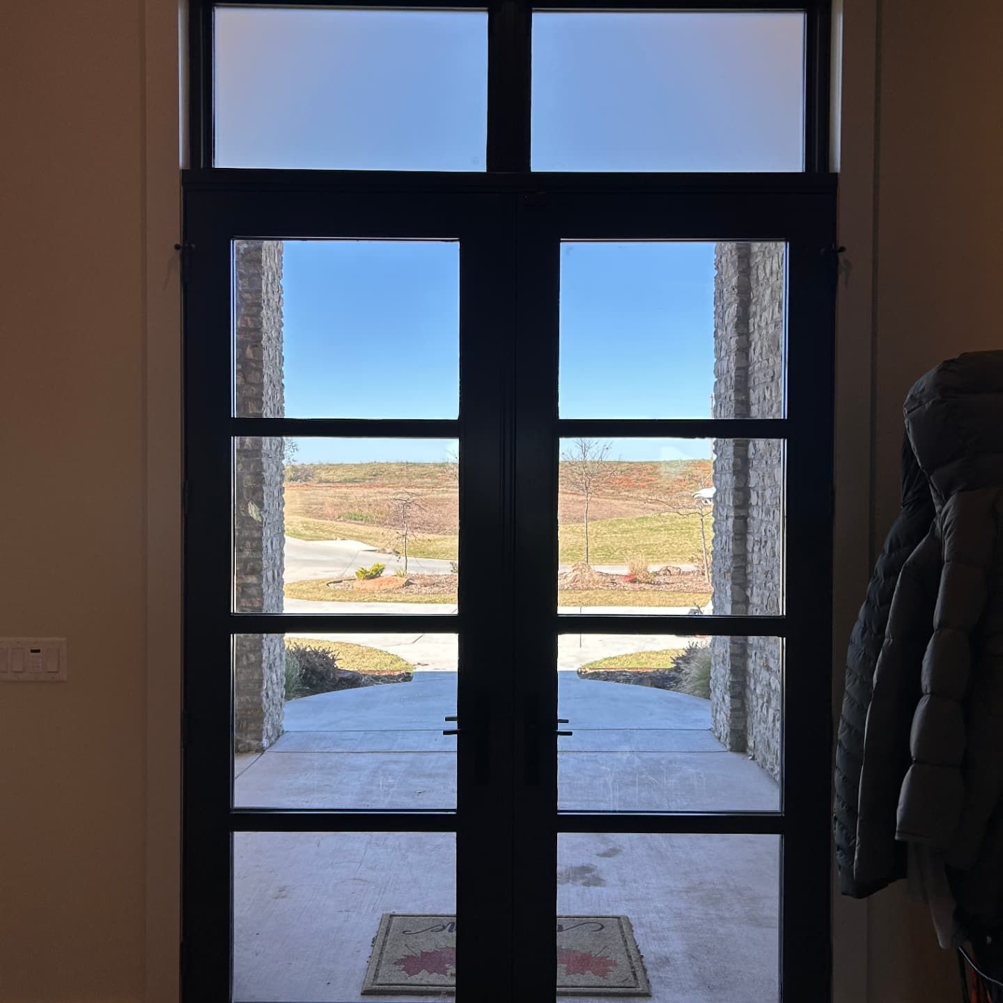 A door with a view of a field and a brick building