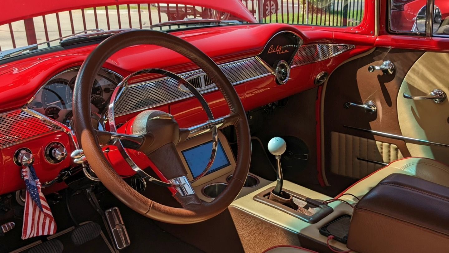 The interior of a red car with a wooden steering wheel.