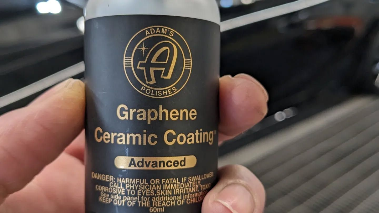 A person is holding a bottle of graphene ceramic coating.