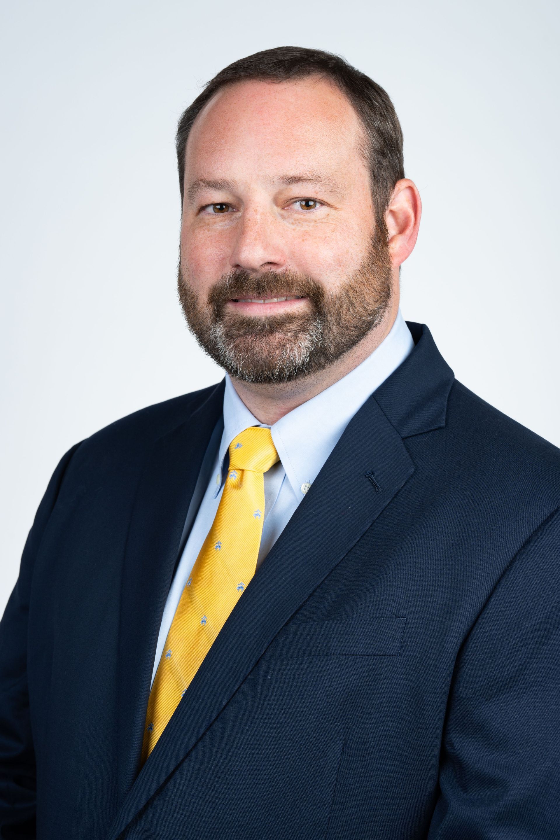 Photo of Dr. Rymer wearing a black suit with a yellow tie