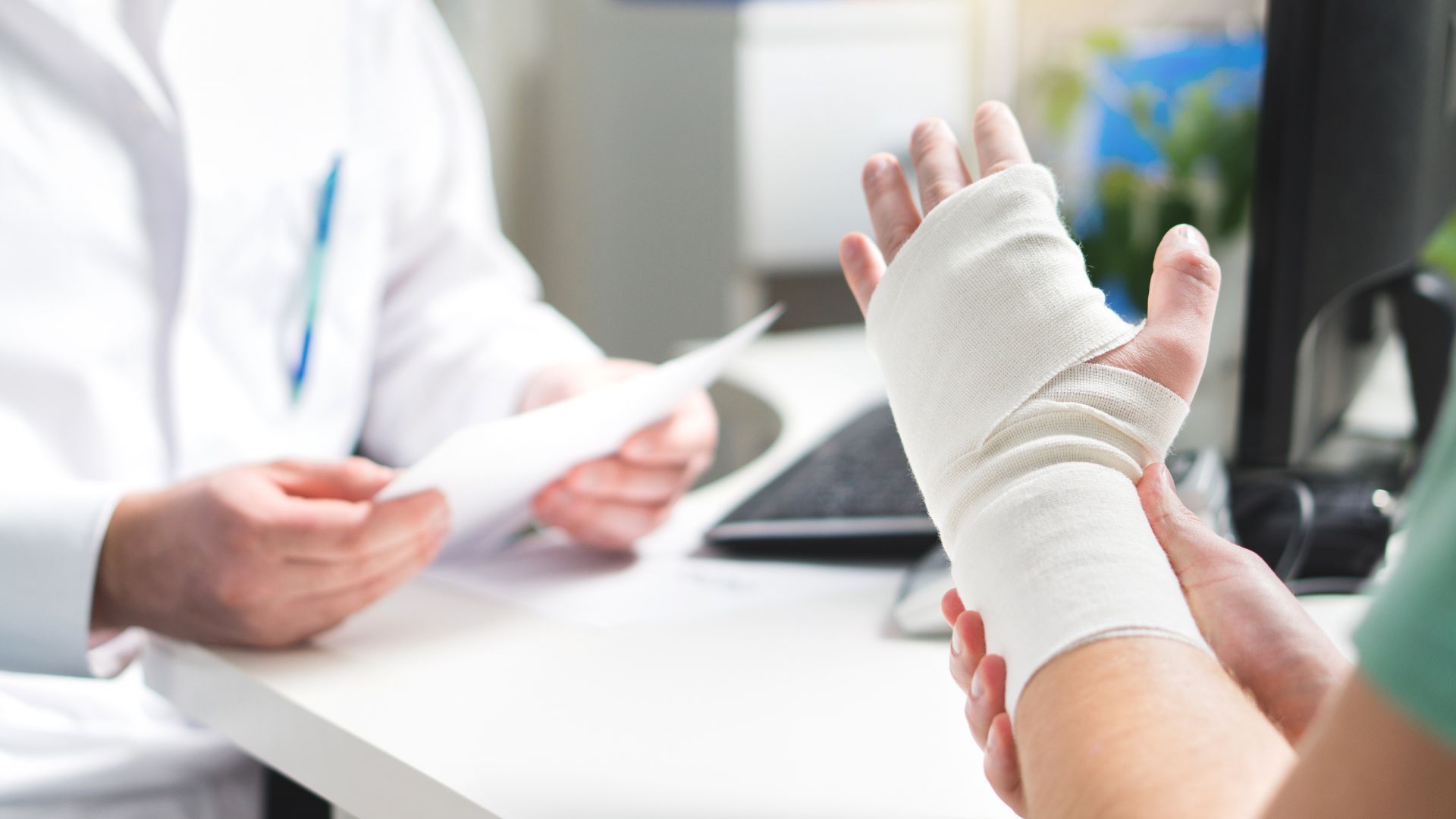 Bandaged hand being examined by a doctor in a clinic office