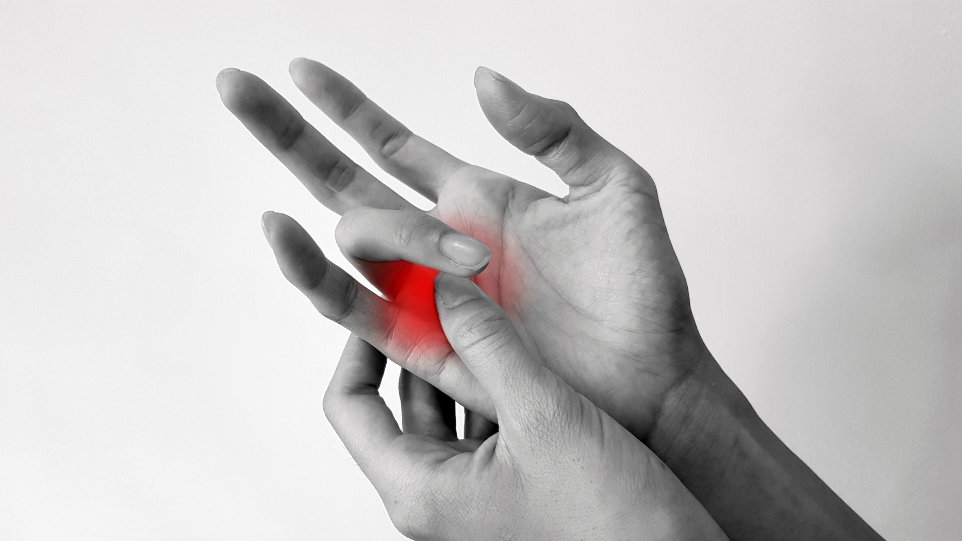 Hands holding a painful red wrist injury on a grayscale background