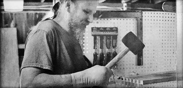 mand with injured hand using rubber mallet in workshop