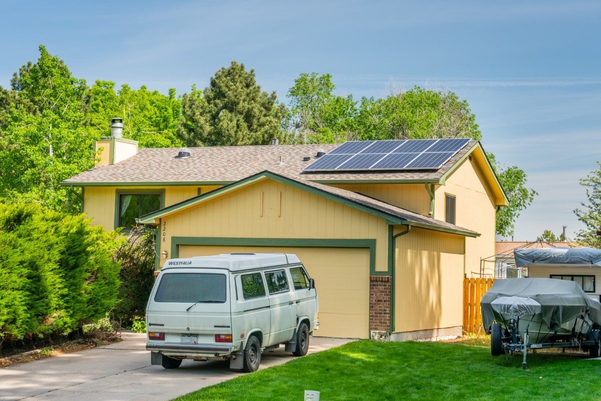 A van is parked in front of a house with solar panels on the roof.