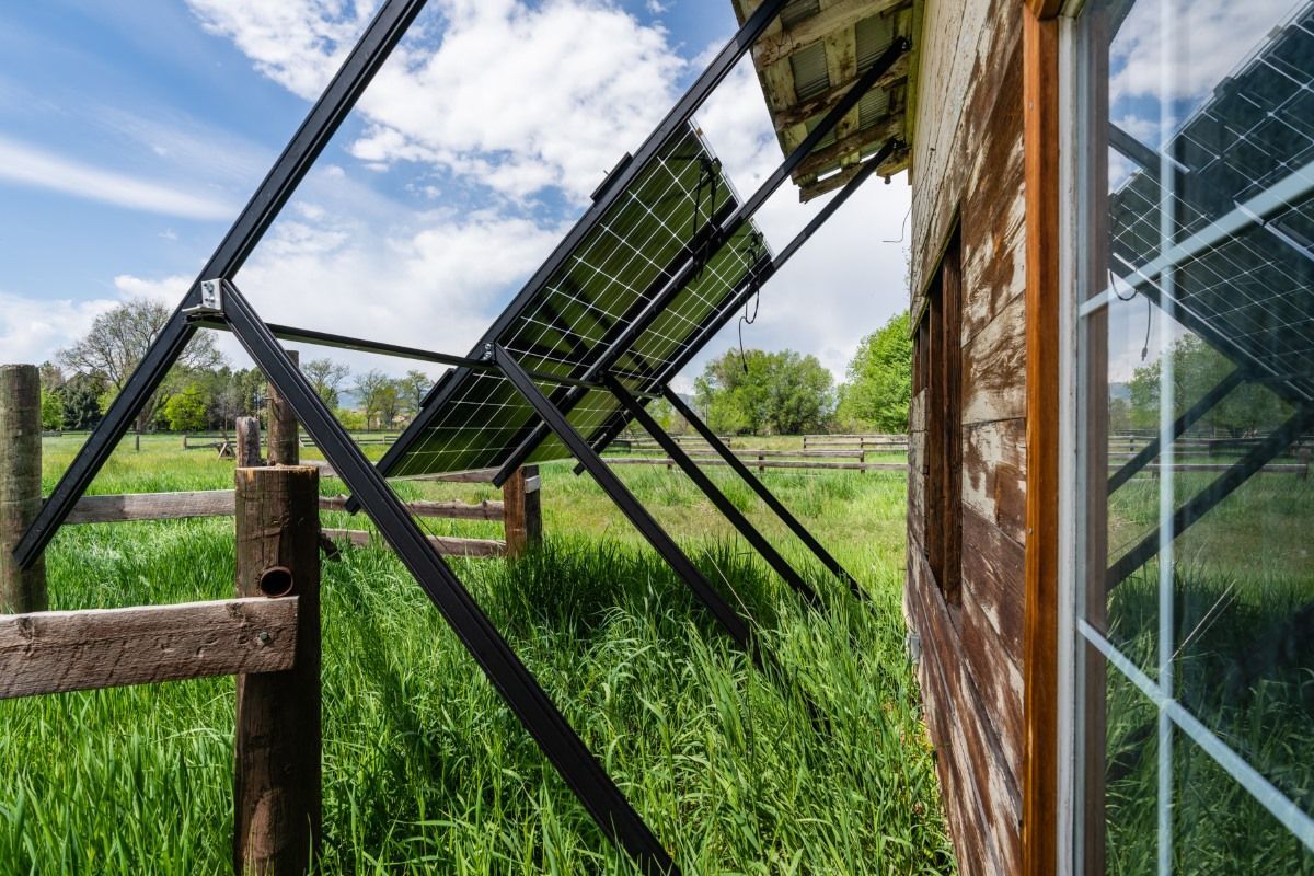A house with solar panels on the side of it in a field.