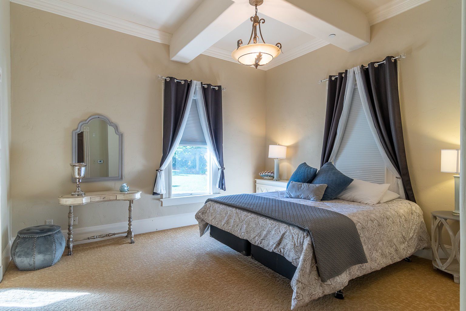 A bedroom with a bed , dresser , mirror and window.