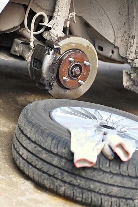 Un neumático está en el suelo al lado de un coche.