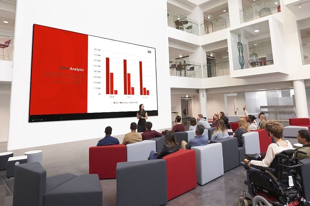 A group of people are sitting in chairs in front of a large screen.