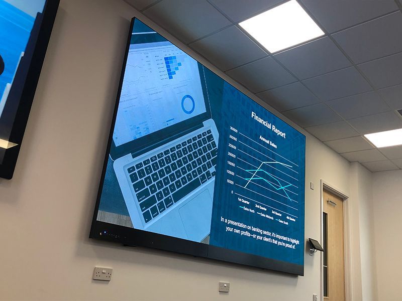 A large screen with a laptop on it is hanging on a wall.