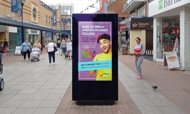 A large billboard with a picture of a man on it is on a sidewalk.