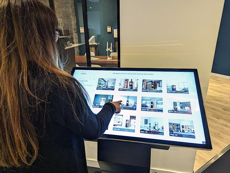 A woman is using a touchscreen display in a store.