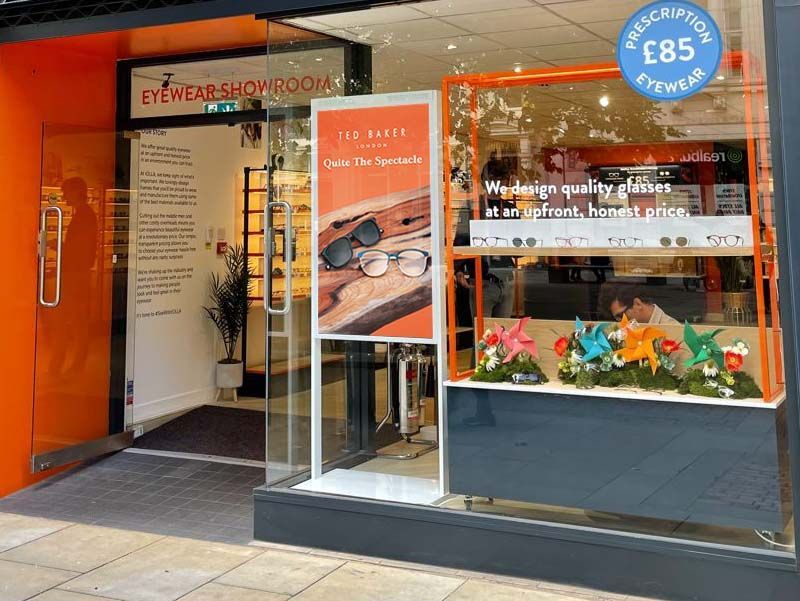 A store front with a sign that says prescription eyewear on it.