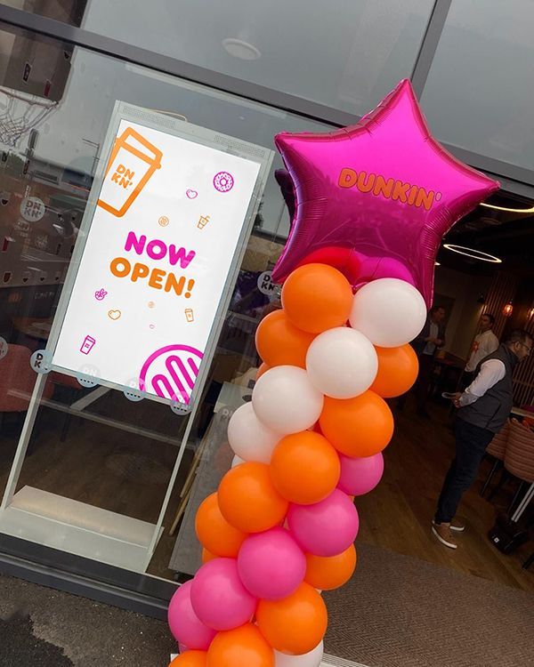 A dunkin donuts sign is surrounded by balloons