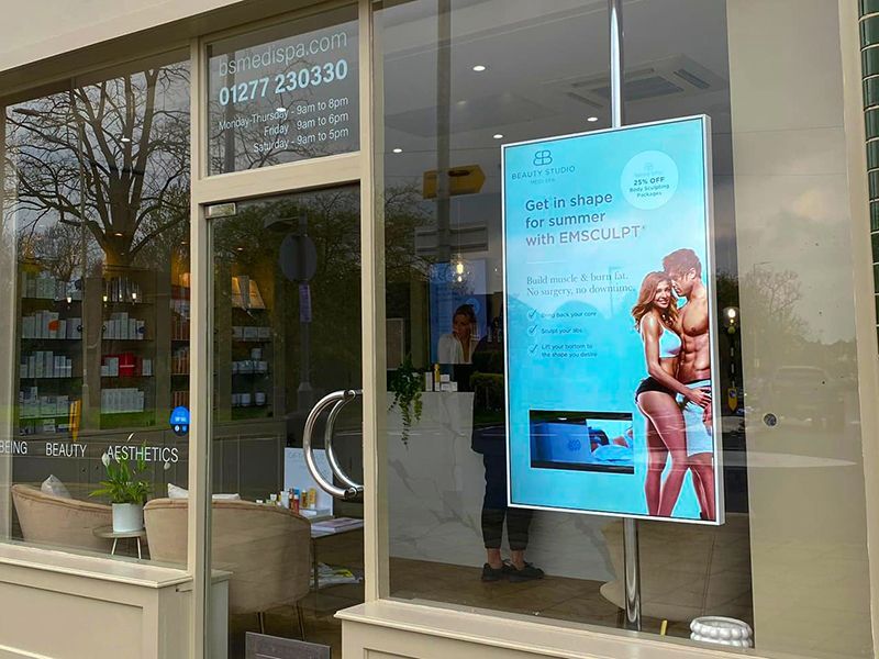 A man and woman are kissing in a store window.