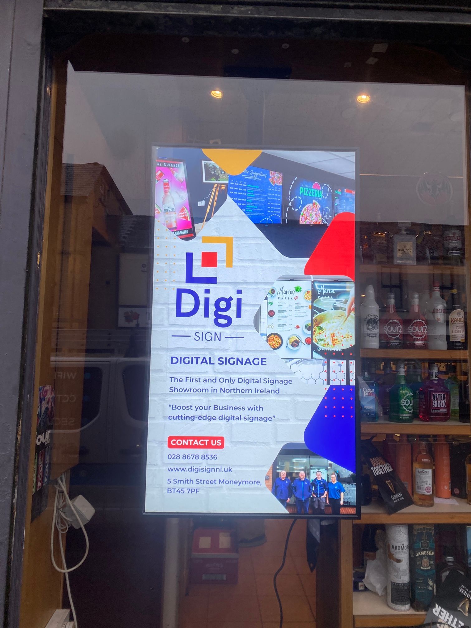 A digital sign is hanging on a glass door in a store.