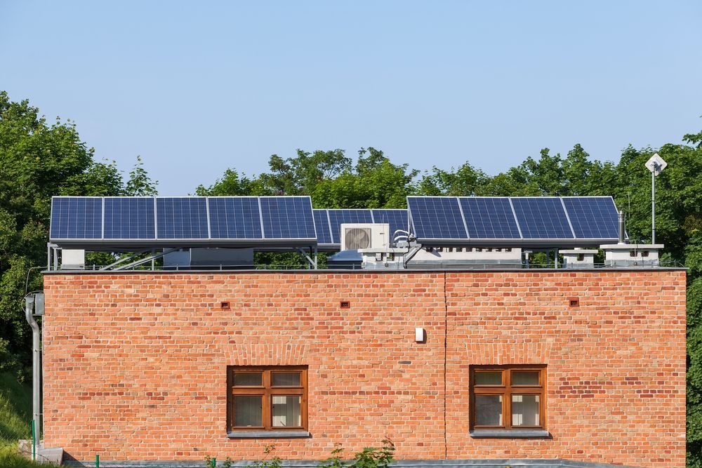 A Brick Building With Solar Panels On The Roof — Rapidcool Air Conditioning & Electrical In Shellharbour, NSW