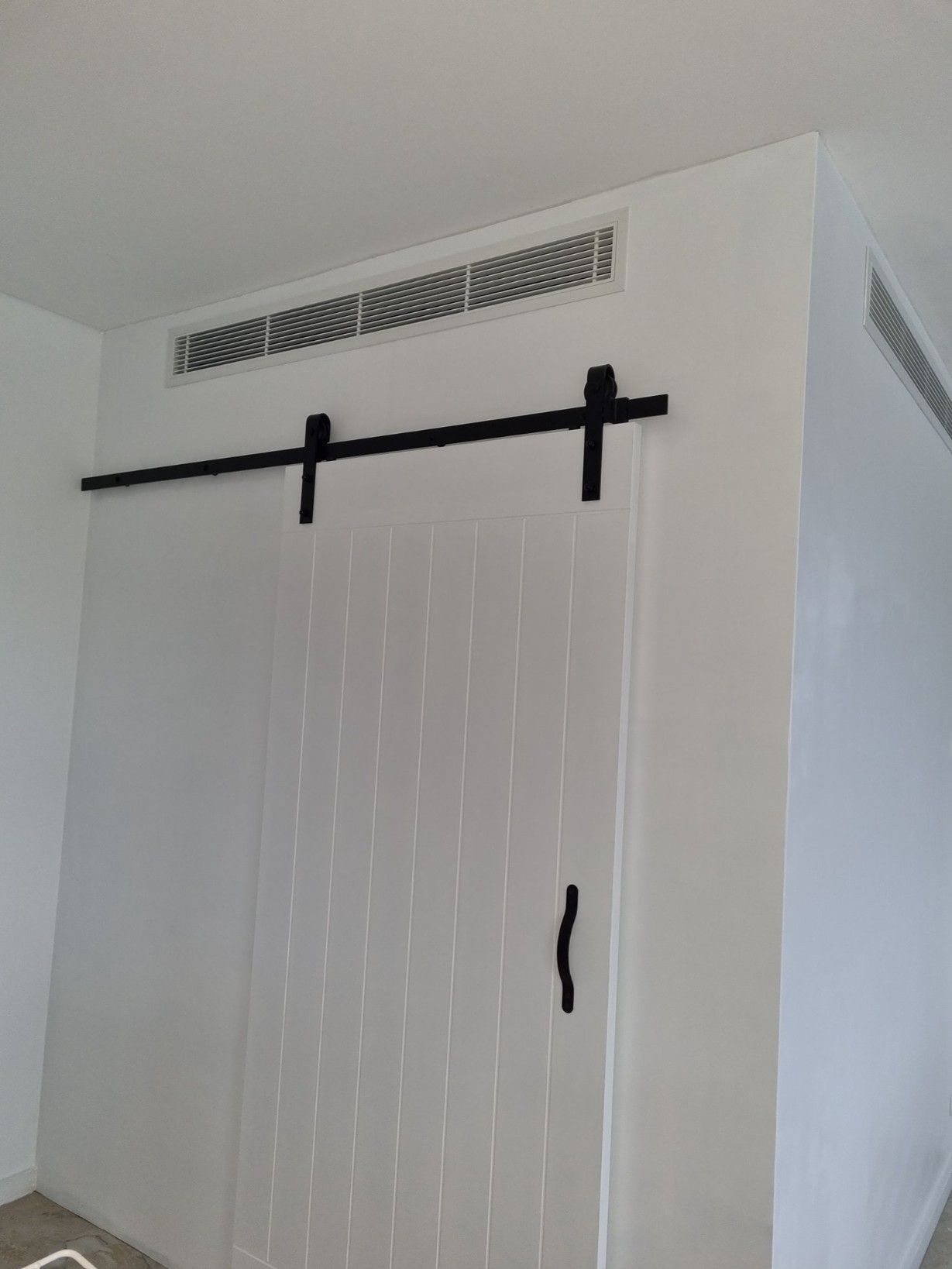 A Sliding Barn Door Is Hanging On A White Wall In A Room — Rapidcool Air Conditioning & Electrical In Dapto, NSW