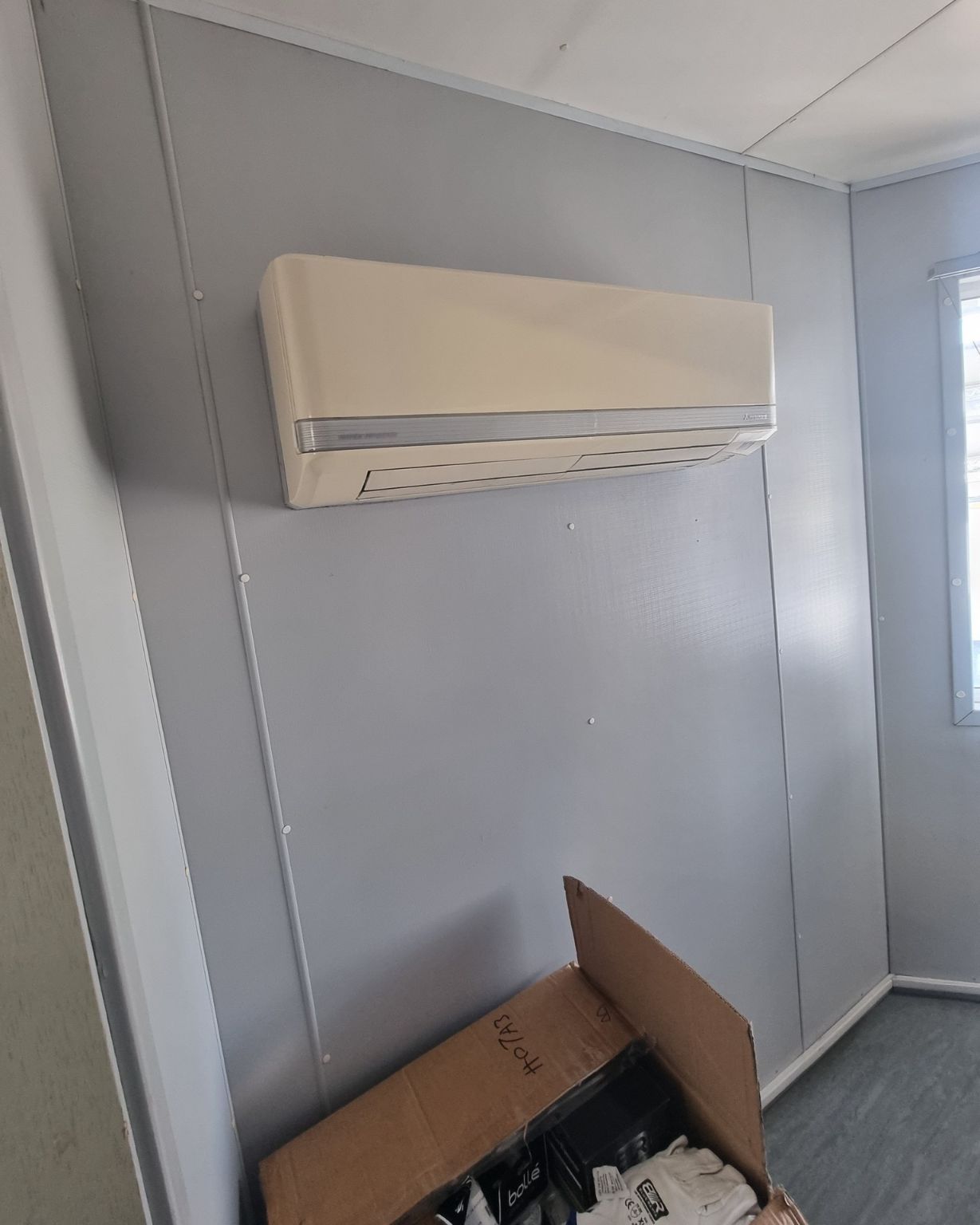 A Room With A Box On The Floor And An Air Conditioner — Rapidcool Air Conditioning & Electrical In Fairy Meadow, NSW