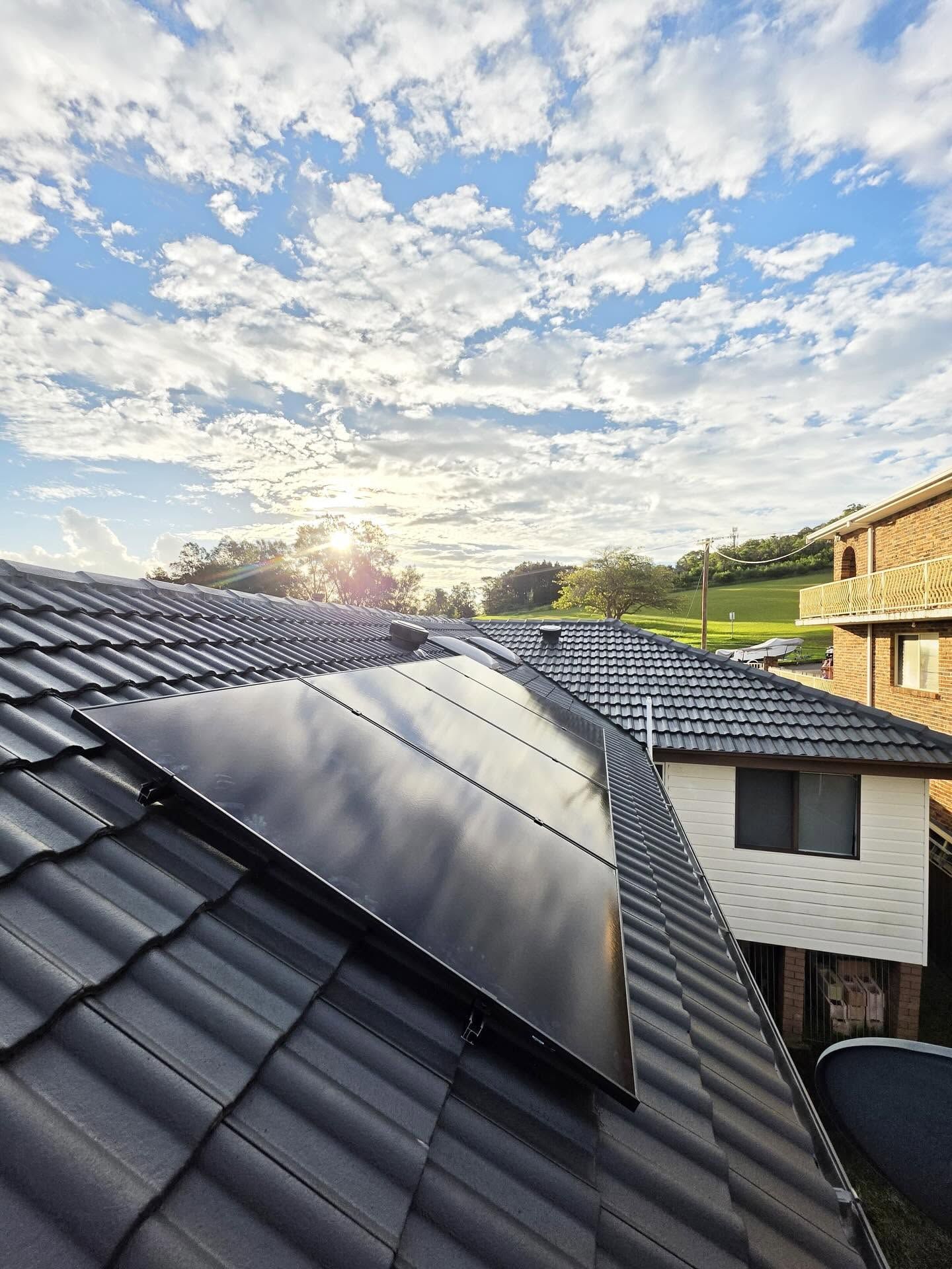 Solar Roof Panels on a Tiled Rooftop at Sunset — Rapidcool Air Conditioning, Electrical & Solar In Unanderra, NSW
