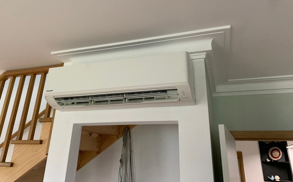 A Room With A Staircase And A Wall Mounted Air Conditioner — Rapidcool Air Conditioning & Electrical In Dapto, NSW