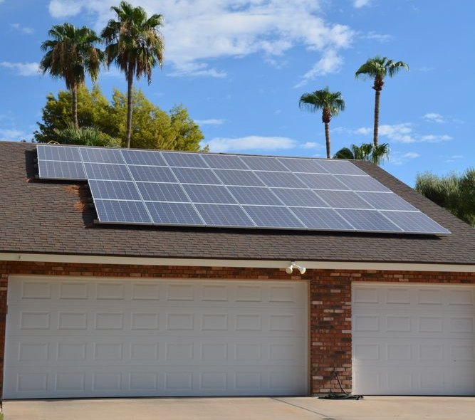 Solar panels installed on a house roof under a blue sky.