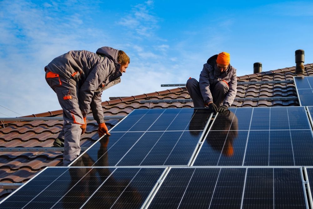 Two Workers Installing Solar Panels On Tile Roof