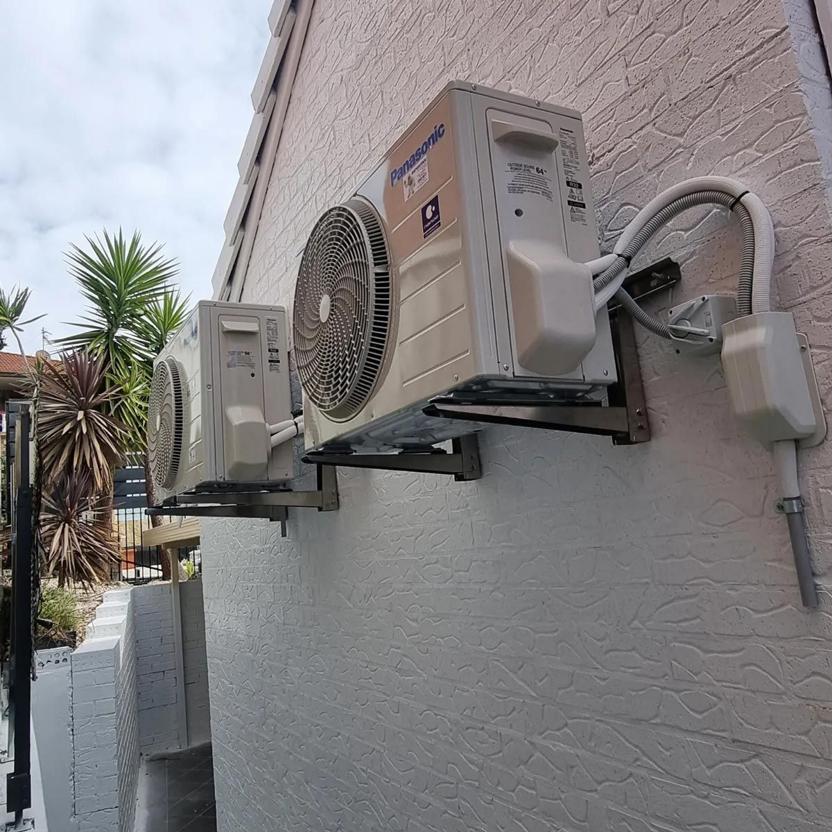Two Air Conditioners Are Mounted On The Side Of A Building — Rapidcool Air Conditioning & Electrical In Dapto, NSW