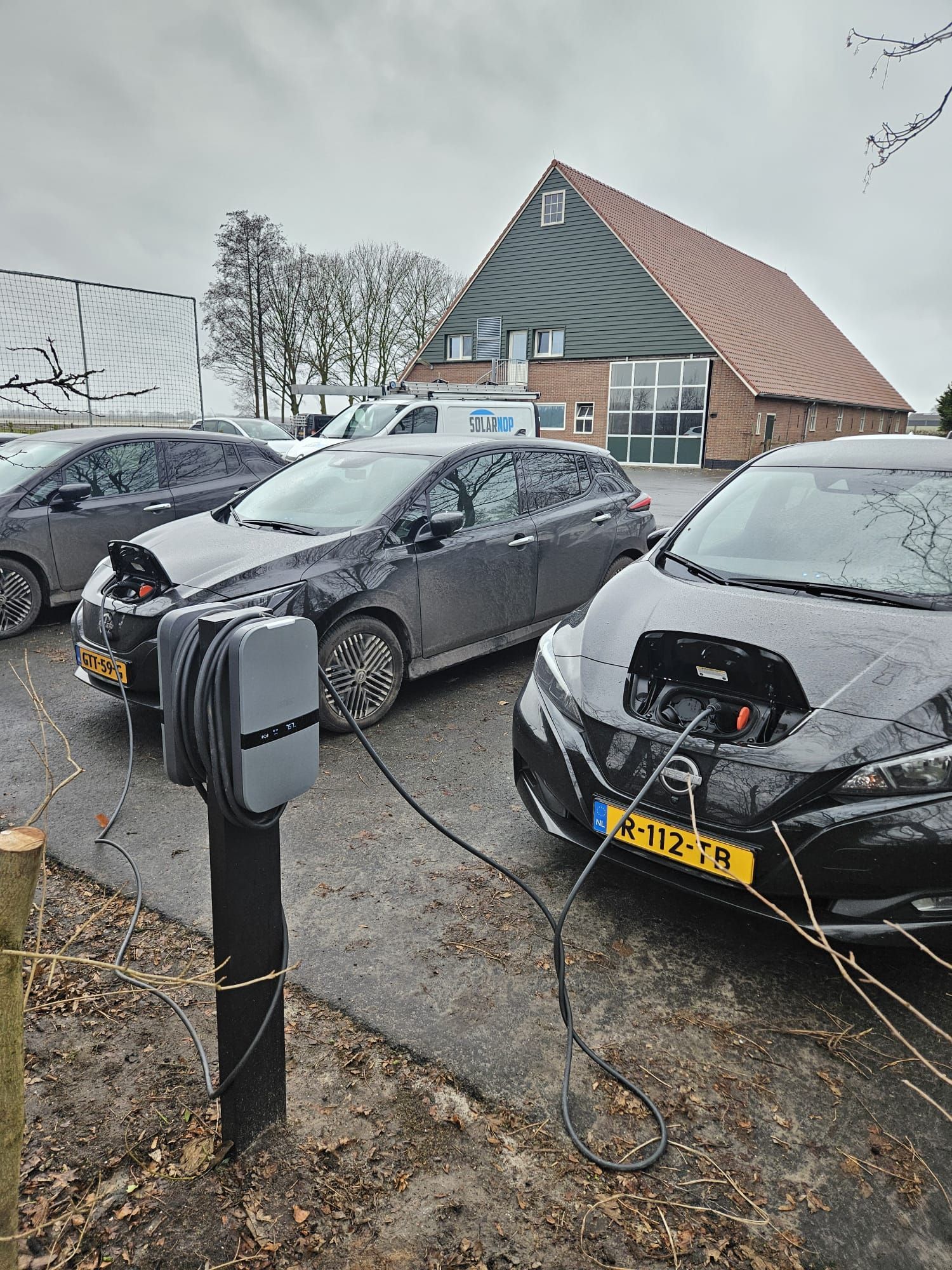 Een laadstation voor een elektrische auto staat aan de zijkant van een oprit.