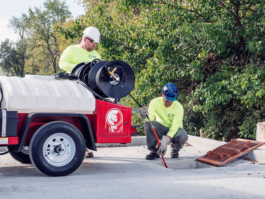 Plumber operating a hydro jetting hose at a drain cleanout