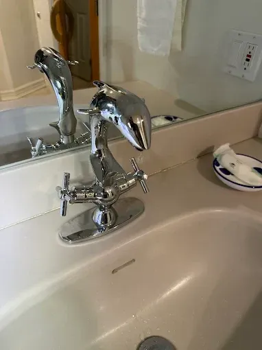 Chrome bathroom faucet over white sink with mirror reflection and soap dish