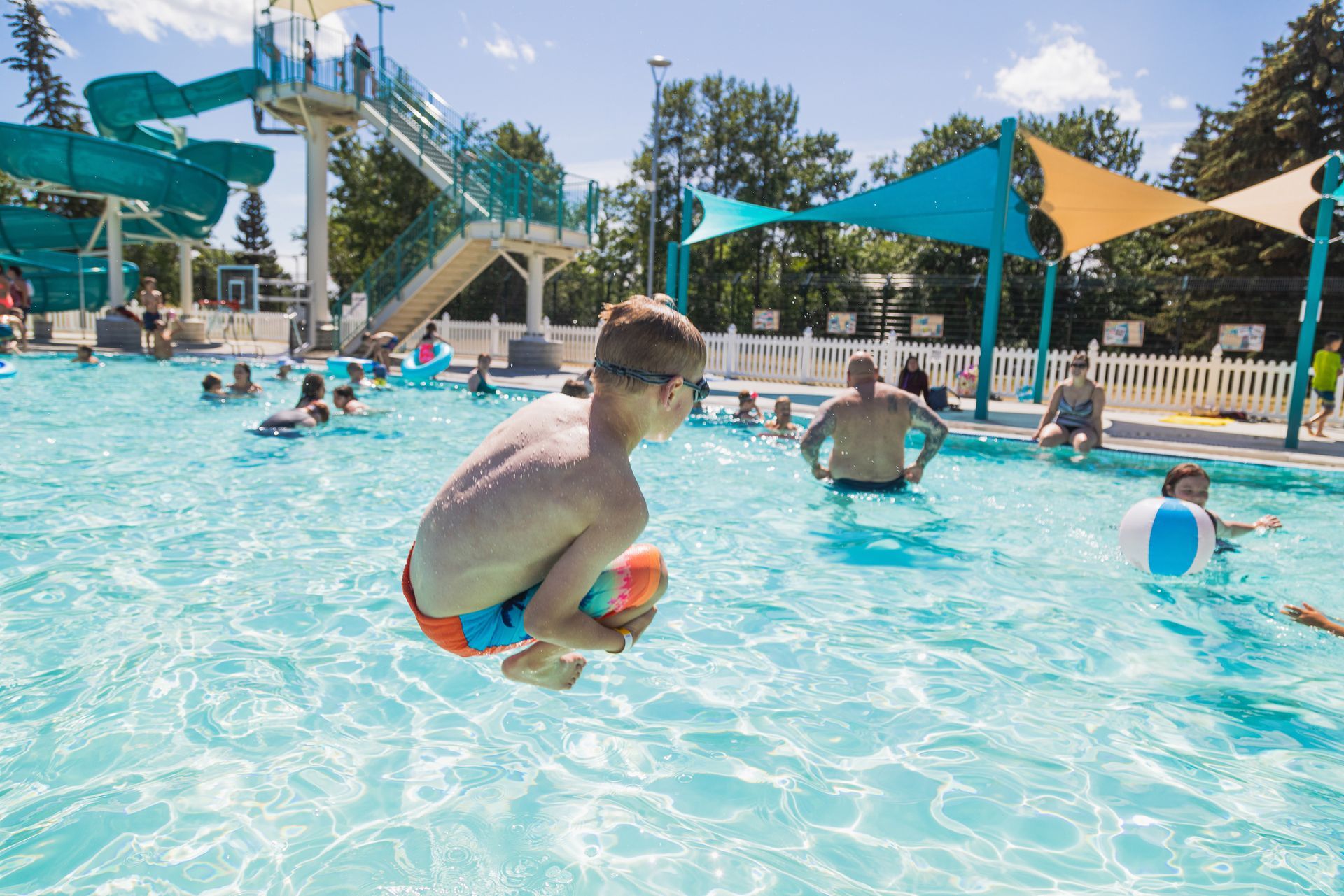 A young boy is jumping into a swimming pool.