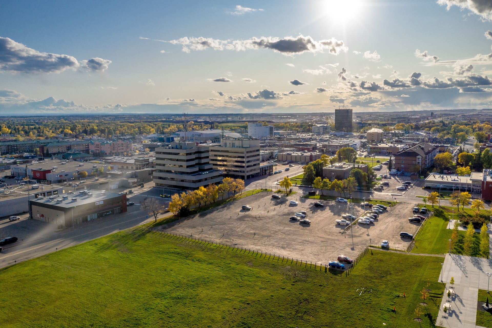 An aerial view of a city with a large grassy field in the foreground.