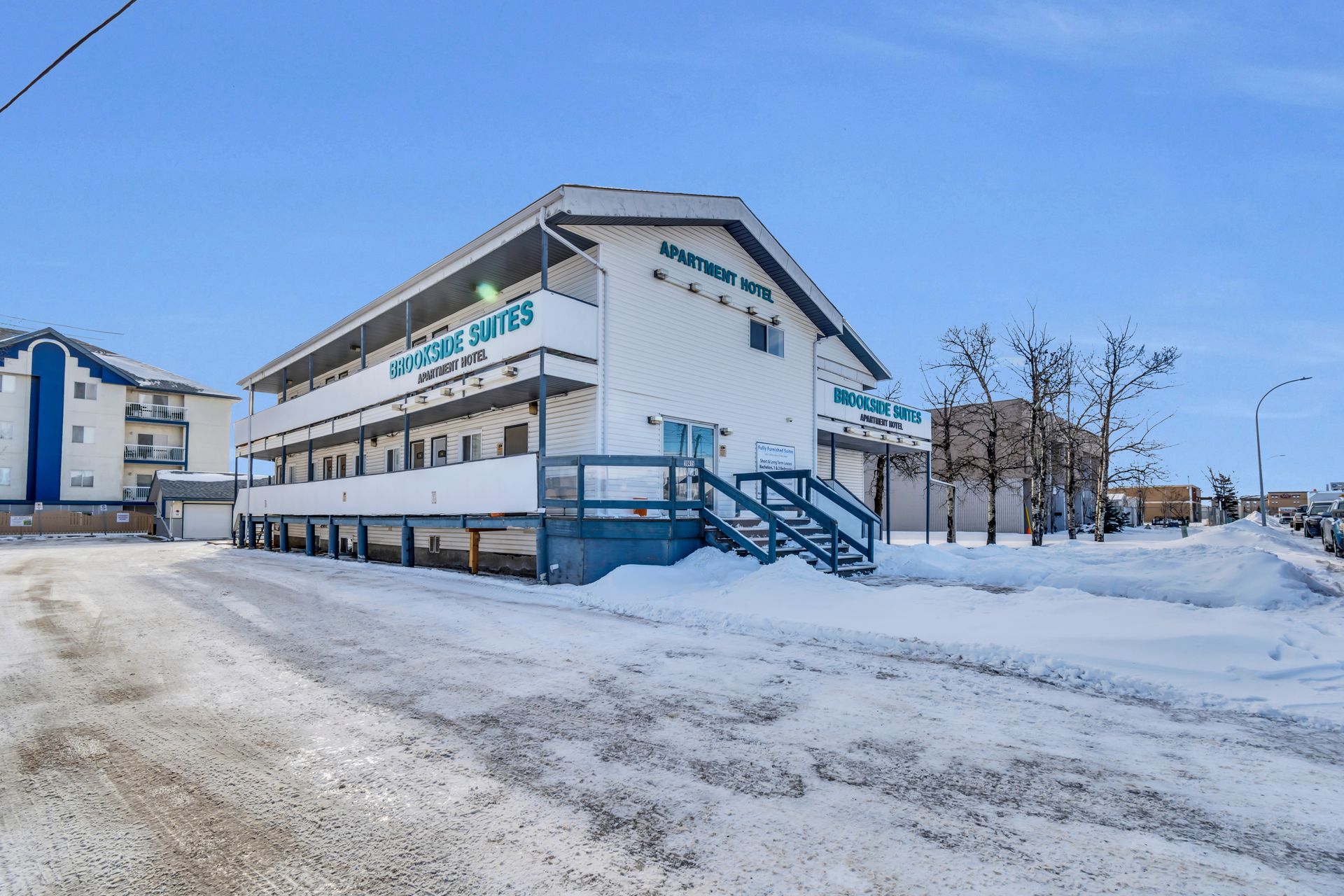 A large white building with stairs leading up to it is covered in snow.