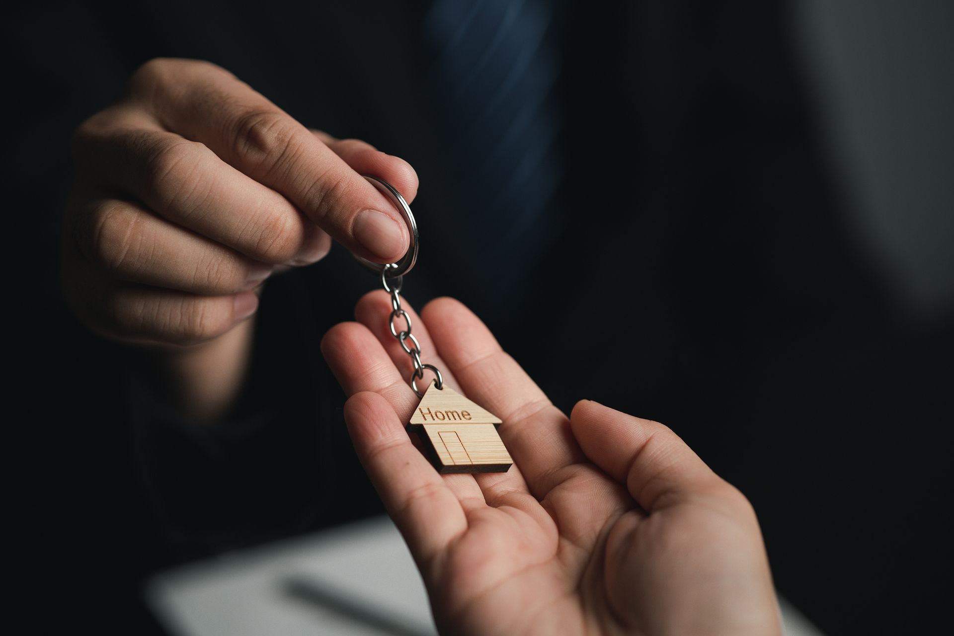 A person is holding a house keychain in their hand.