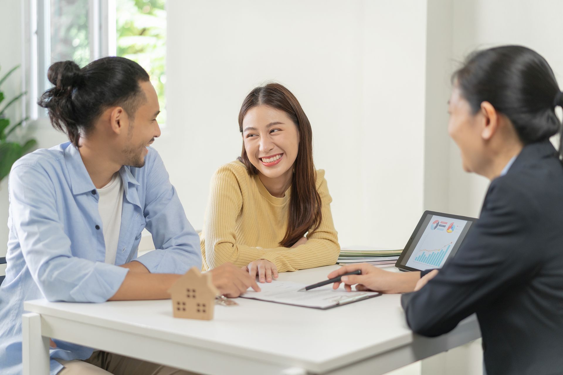 A man and a woman are sitting at a table talking to a real estate agent.