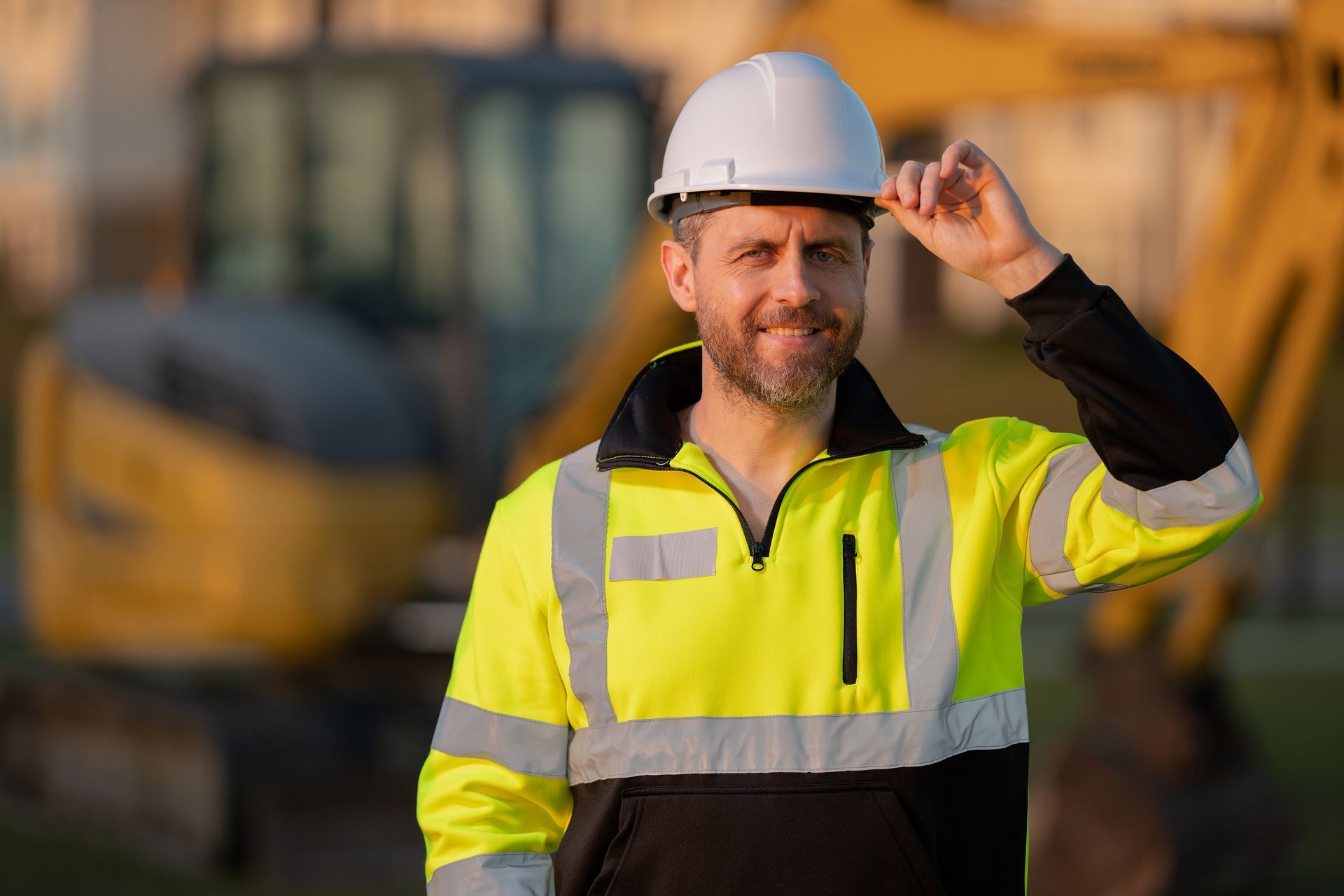 A construction worker wearing a hard hat and safety vest is standing in front of a bulldozer.