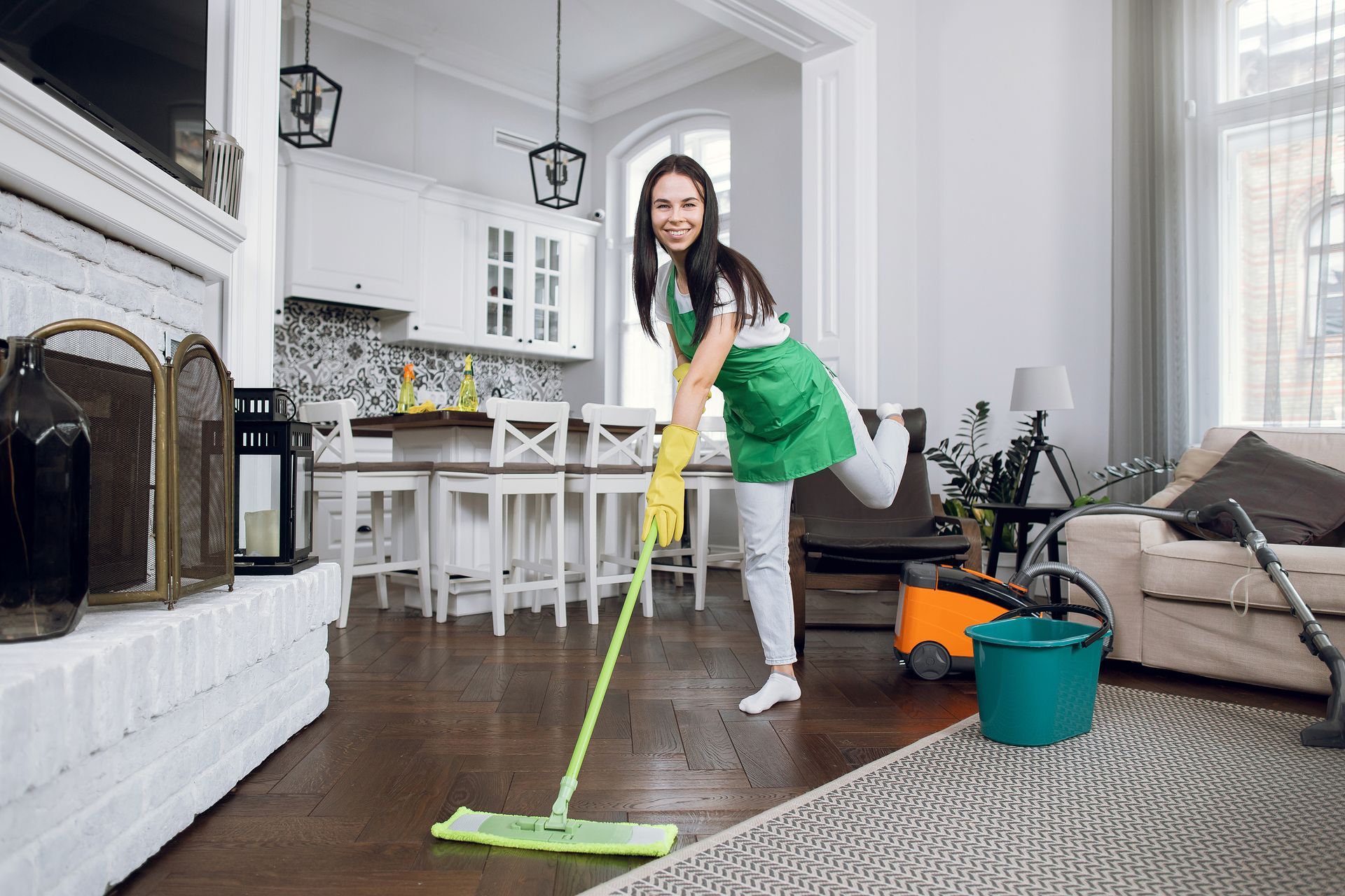 A woman is cleaning the floor of a living room with a mop.